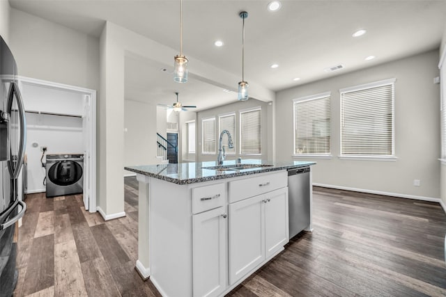 16114 Northern Cardinal Ln, Cypress, TX 77433 - kitchen with washer / dryer, stainless steel appliances, dark stone counters, dark wood-style flooring, and white cabinets