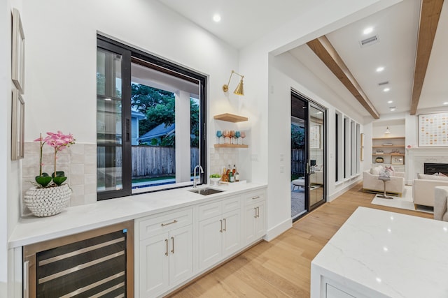 1310 Willard, Houston, TX 77006 - bar featuring beverage cooler, light wood-style floors, backsplash, beamed ceiling, and a fireplace
