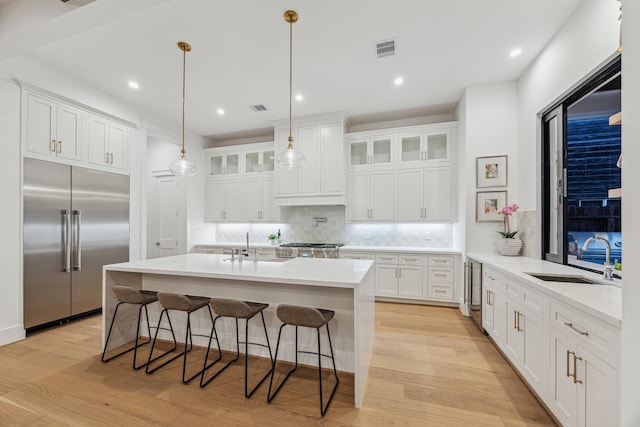 1310 Willard, Houston, TX 77006 - kitchen featuring built in fridge, tasteful backsplash, a kitchen bar, glass insert cabinets, and white cabinets