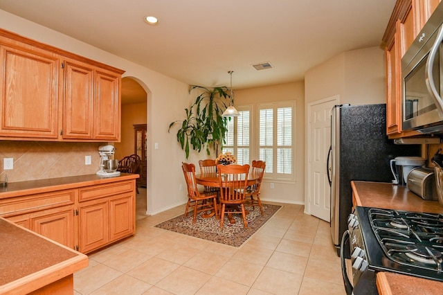 28123 Canyon Wren Dr, Katy, TX 77494 - kitchen featuring stainless steel microwave, arched walkways, tasteful backsplash, light tile patterned floors, and recessed lighting
