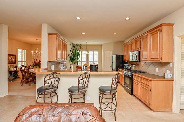 28123 Canyon Wren Dr, Katy, TX 77494 - kitchen with black gas range, stainless steel microwave, light tile patterned floors, a kitchen bar, and recessed lighting