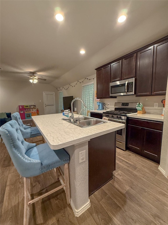 706 Zinnia Ct, Rosharon, TX 77583 - kitchen featuring appliances with stainless steel finishes, dark brown cabinets, light countertops, open floor plan, and light wood-type flooring