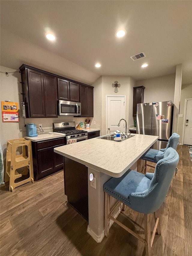 706 Zinnia Ct, Rosharon, TX 77583 - kitchen featuring appliances with stainless steel finishes, dark brown cabinetry, light countertops, dark wood-style floors, and a breakfast bar