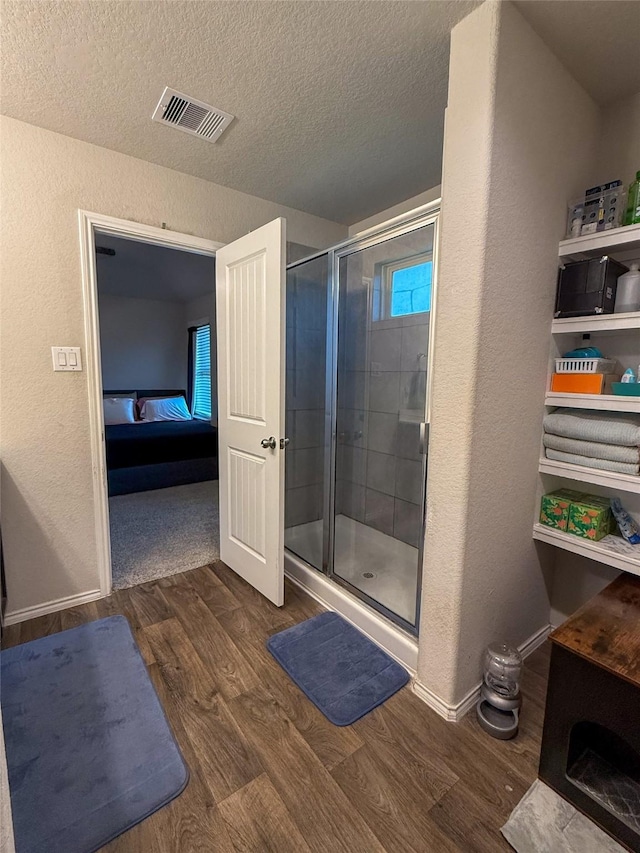 706 Zinnia Ct, Rosharon, TX 77583 - ensuite bathroom featuring a textured wall, wood finished floors, a stall shower, and a textured ceiling
