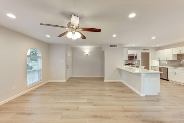 22843 Post Gate Dr, Spring, TX 77373 - kitchen featuring appliances with stainless steel finishes, a peninsula, backsplash, light countertops, and white cabinetry