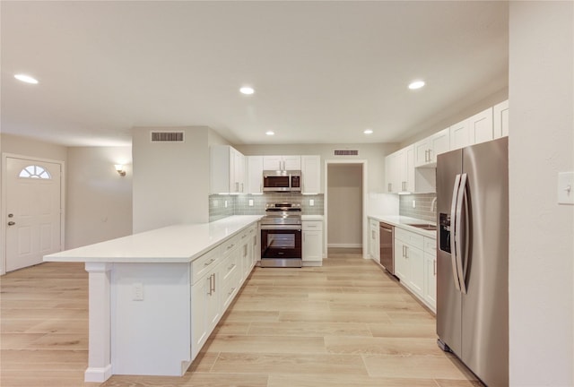 22843 Post Gate Dr, Spring, TX 77373 - kitchen with appliances with stainless steel finishes, a peninsula, tasteful backsplash, white cabinetry, and light countertops
