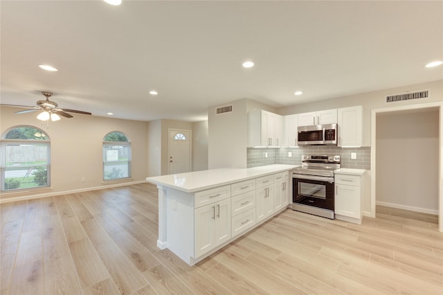 22843 Post Gate Dr, Spring, TX 77373 - kitchen with appliances with stainless steel finishes, a peninsula, light wood finished floors, light countertops, and recessed lighting