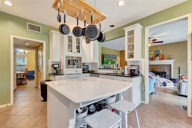 2605 Broussard Ct, Seabrook, TX 77586 - kitchen featuring appliances with stainless steel finishes, light tile patterned floors, glass insert cabinets, white cabinets, and recessed lighting