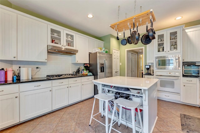 2605 Broussard Ct, Seabrook, TX 77586 - kitchen with stainless steel appliances, light tile patterned flooring, backsplash, white cabinets, and recessed lighting