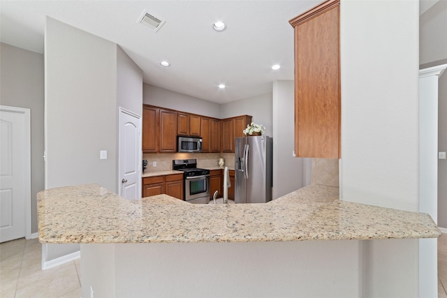 28035 Emma Gardens Ln, Spring, TX 77386 - kitchen with stainless steel appliances, light tile patterned floors, light stone countertops, a peninsula, and recessed lighting