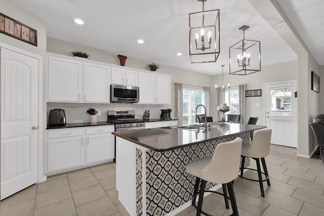 2803 Ridgecliff Ct, Conroe, TX 77301 - kitchen featuring stainless steel appliances, a chandelier, dark countertops, backsplash, and an island with sink