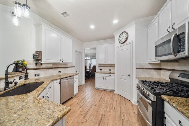 6107 Kyle Bend Ln, Katy, TX 77493 - kitchen featuring stainless steel appliances, recessed lighting, light stone countertops, white cabinetry, and crown molding