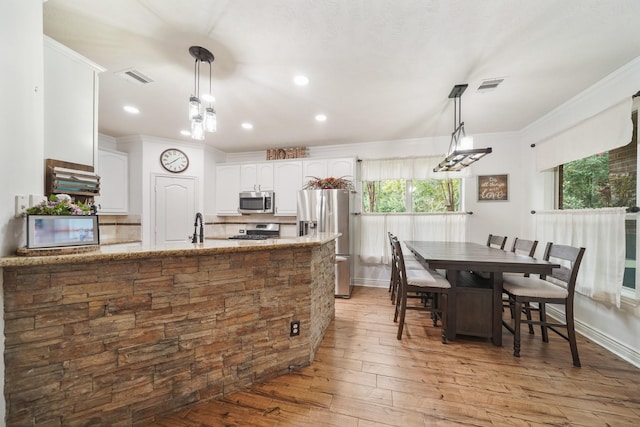 6107 Kyle Bend Ln, Katy, TX 77493 - kitchen with stainless steel appliances, white cabinets, crown molding, light stone countertops, and light wood-style flooring
