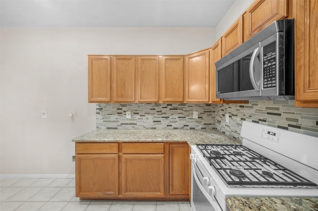 13535 San Martin Ln, Houston, TX 77083 - kitchen with stainless steel microwave, gas range gas stove, decorative backsplash, light stone counters, and light tile patterned floors