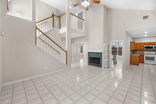 13535 San Martin Ln, Houston, TX 77083 - unfurnished living room featuring high vaulted ceiling, a ceiling fan, light tile patterned flooring, stairway, and a tiled fireplace