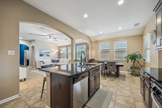 213 Lighthouse Bay Ln, League City, TX 77539 - kitchen featuring stainless steel dishwasher, arched walkways, a kitchen bar, dark brown cabinets, and dark stone counters