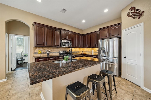 213 Lighthouse Bay Ln, League City, TX 77539 - kitchen featuring stainless steel appliances, backsplash, light tile patterned flooring, a kitchen breakfast bar, and dark stone counters