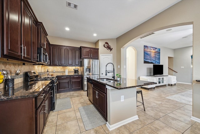 213 Lighthouse Bay Ln, League City, TX 77539 - kitchen with stainless steel appliances, a breakfast bar area, arched walkways, backsplash, and dark stone countertops