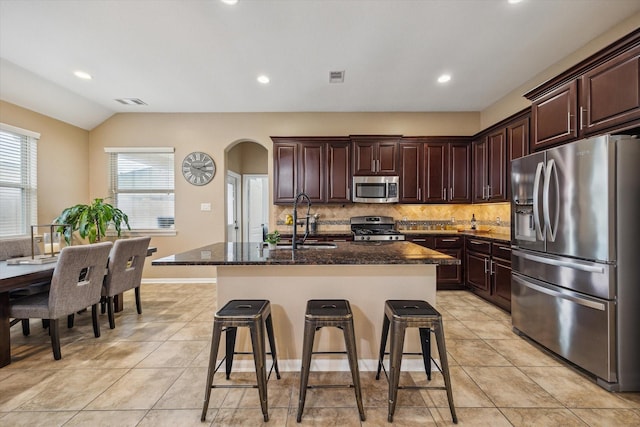 213 Lighthouse Bay Ln, League City, TX 77539 - kitchen featuring stainless steel appliances, backsplash, arched walkways, a breakfast bar, and light tile patterned flooring