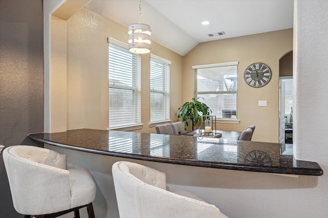213 Lighthouse Bay Ln, League City, TX 77539 - kitchen featuring a textured wall, vaulted ceiling, arched walkways, a peninsula, and pendant lighting
