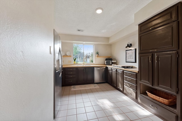 8411 Lylewood Ct, Houston, TX 77040 - kitchen with appliances with stainless steel finishes, a textured ceiling, light countertops, light tile patterned floors, and dark brown cabinetry