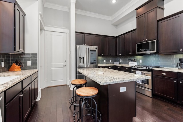 5825 Petty St, Houston, TX 77007 - kitchen featuring stainless steel appliances, a breakfast bar, ornamental molding, dark wood-style flooring, and dark brown cabinets