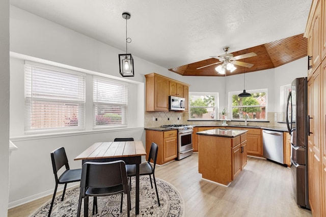 10603 Wagon Trail Rd, Houston, TX 77064 - kitchen with appliances with stainless steel finishes, a ceiling fan, light wood-style flooring, a center island, and decorative backsplash