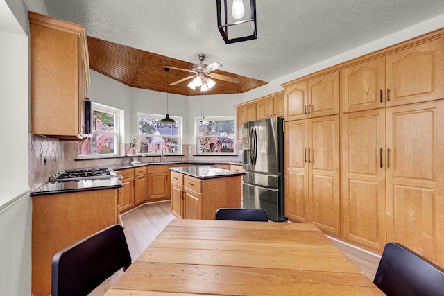 10603 Wagon Trail Rd, Houston, TX 77064 - kitchen with appliances with stainless steel finishes, a ceiling fan, light wood-style flooring, a center island, and decorative backsplash