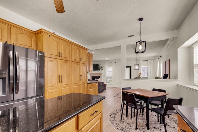 10603 Wagon Trail Rd, Houston, TX 77064 - kitchen featuring stainless steel refrigerator with ice dispenser, ceiling fan, light wood-style floors, hanging light fixtures, and dark stone counters