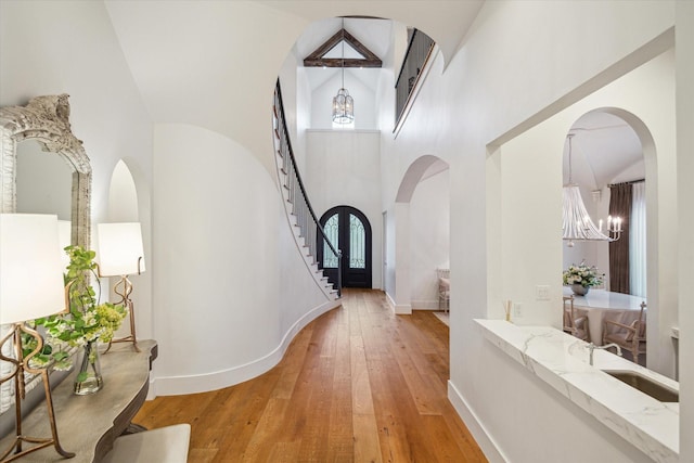 3835 Merrick St, Houston, TX 77025 - entryway featuring a chandelier, a towering ceiling, light wood finished floors, stairway, and arched walkways
