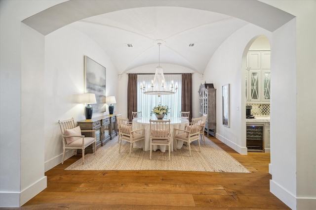 3835 Merrick St, Houston, TX 77025 - dining space with beverage cooler, a chandelier, hardwood / wood-style flooring, and arched walkways