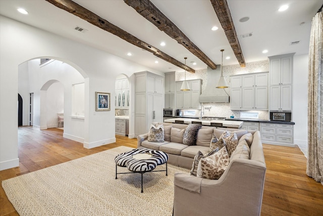 3835 Merrick St, Houston, TX 77025 - living room with arched walkways, light wood finished floors, beam ceiling, and recessed lighting