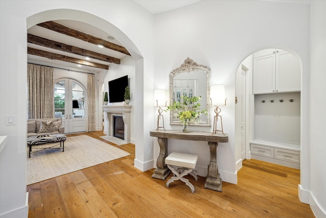 3835 Merrick St, Houston, TX 77025 - entrance foyer with light wood-style flooring, beam ceiling, arched walkways, a fireplace with flush hearth, and french doors