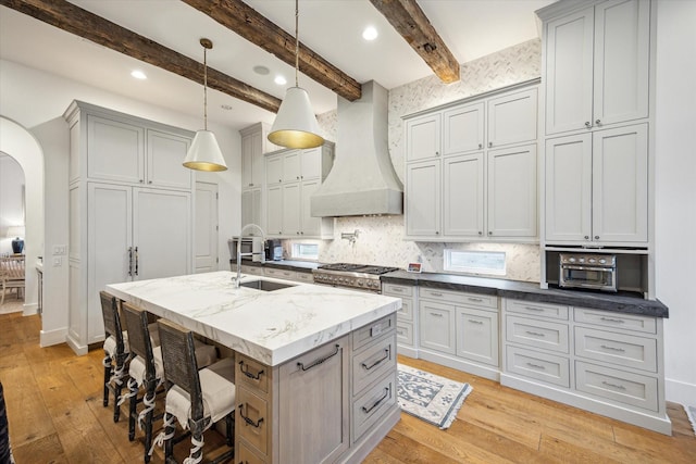 3835 Merrick St, Houston, TX 77025 - kitchen with custom exhaust hood, arched walkways, light wood-style flooring, backsplash, and recessed lighting