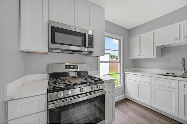 1705 13th St, Galena Park, TX 77547 - kitchen featuring appliances with stainless steel finishes, white cabinets, and light wood-type flooring