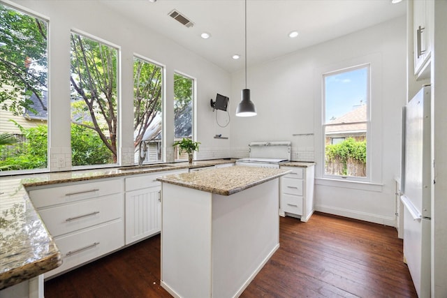 519 Bayland Ave, Houston, TX 77009 - kitchen featuring freestanding refrigerator, white cabinetry, dark wood finished floors, light stone countertops, and tasteful backsplash