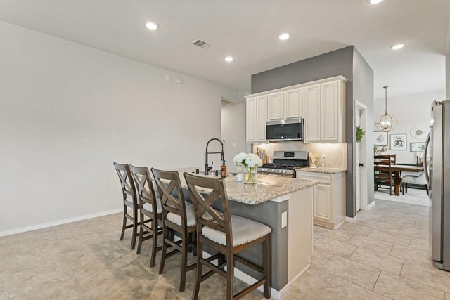 18015 Van Berkel Ln, Houston, TX 77044 - kitchen with stainless steel appliances, light stone countertops, tasteful backsplash, a kitchen bar, and a kitchen island with sink