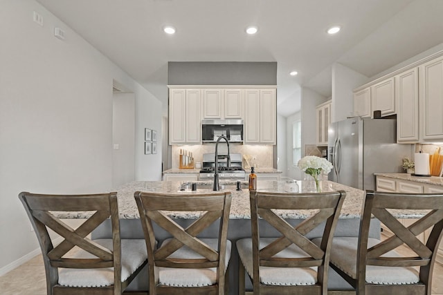 18015 Van Berkel Ln, Houston, TX 77044 - kitchen with stainless steel appliances, decorative backsplash, light stone countertops, a kitchen bar, and recessed lighting