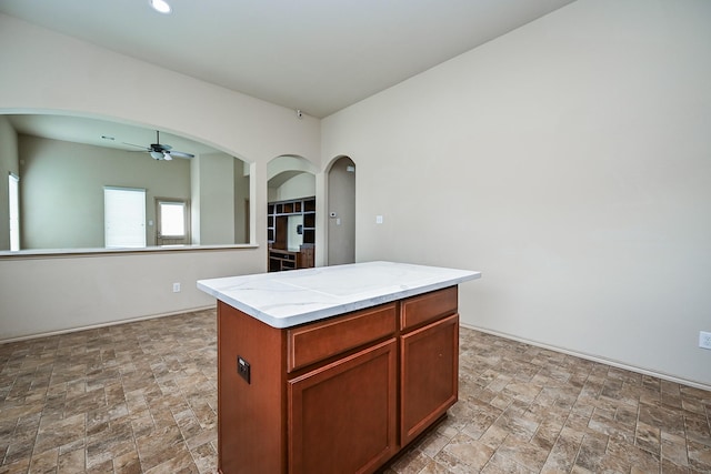 20603 Flintoff Ln, Katy, TX 77449 - kitchen featuring ceiling fan, stone finish flooring, arched walkways, and a kitchen island