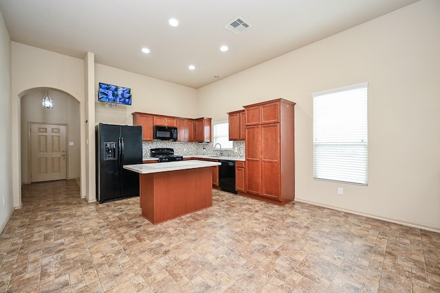20603 Flintoff Ln, Katy, TX 77449 - kitchen with black appliances, a kitchen island, light countertops, stone finish flooring, and arched walkways