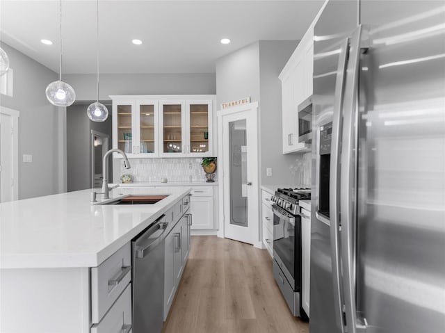 1200 Sailfish Dr, Bay City, TX 77414 - kitchen with stainless steel appliances, an island with sink, light countertops, glass insert cabinets, and white cabinetry