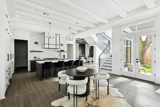 1220 Bomar St, Houston, TX 77006 - dining room featuring dark wood-style floors, beamed ceiling, a chandelier, french doors, and stairs