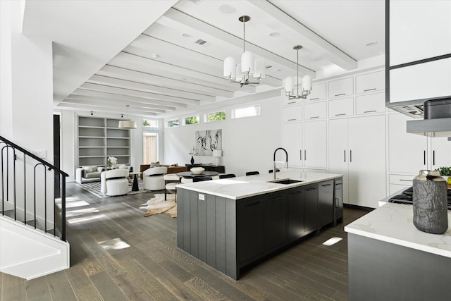 1220 Bomar St, Houston, TX 77006 - kitchen with dark wood finished floors, a chandelier, white cabinetry, light stone counters, and beam ceiling