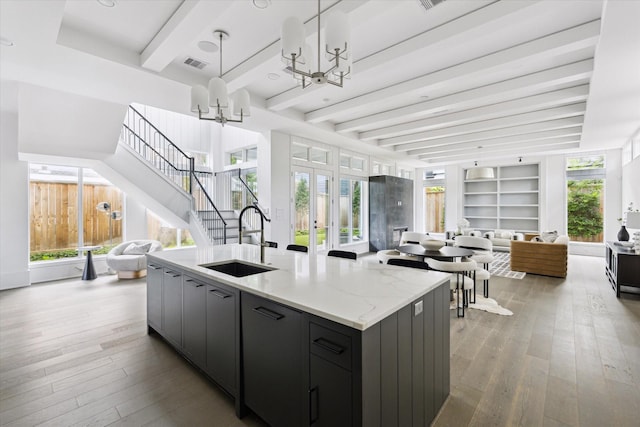 1220 Bomar St, Houston, TX 77006 - kitchen with open floor plan, beamed ceiling, a chandelier, wood-type flooring, and a center island with sink