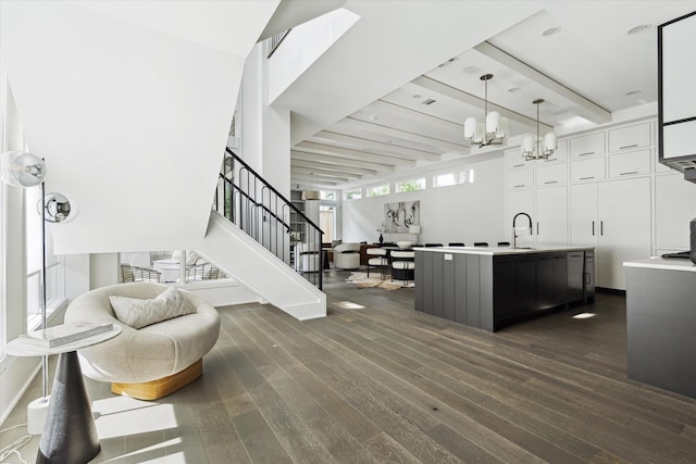 1220 Bomar St, Houston, TX 77006 - kitchen featuring dark wood-style flooring, a chandelier, white cabinetry, beam ceiling, and a kitchen island with sink