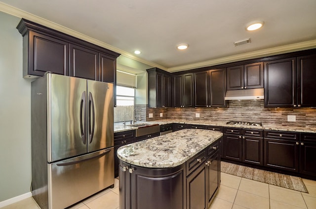 4415 Crimson Ct, Sugar Land, TX 77479 - kitchen with stainless steel appliances, under cabinet range hood, light tile patterned floors, a kitchen island, and light stone countertops