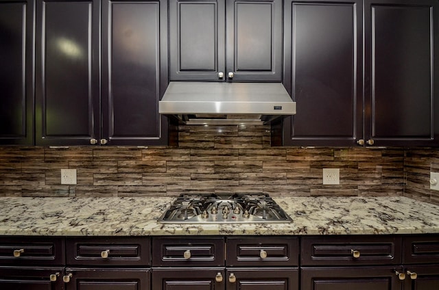 4415 Crimson Ct, Sugar Land, TX 77479 - kitchen with under cabinet range hood, stainless steel gas cooktop, tasteful backsplash, light stone countertops, and dark brown cabinets