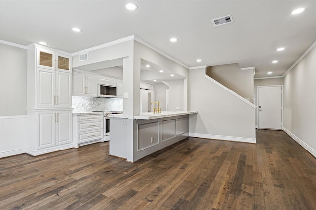 974 Memorial Village Dr Unit 53, Houston, TX 77024 - kitchen featuring white appliances, ornamental molding, dark wood finished floors, white cabinetry, and a peninsula