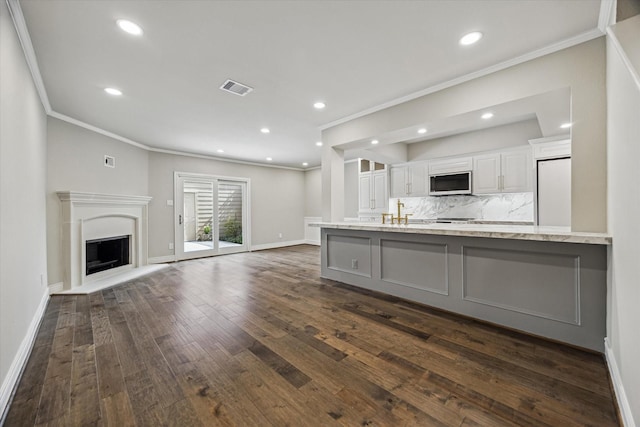 974 Memorial Village Dr Unit 53, Houston, TX 77024 - kitchen with white microwave, crown molding, a fireplace with raised hearth, dark wood-style flooring, and white cabinetry