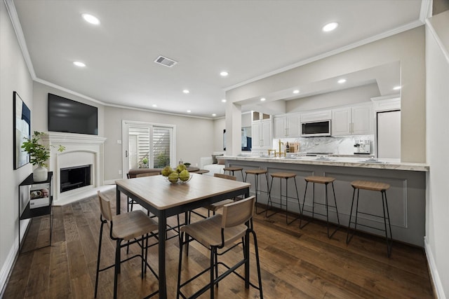 974 Memorial Village Dr Unit 53, Houston, TX 77024 - dining area featuring crown molding, dark wood-type flooring, a fireplace with raised hearth, and recessed lighting